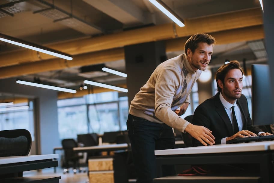 Man training another man at computer desk